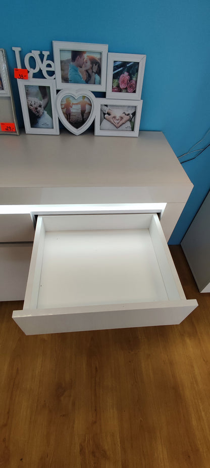 Wysunięta jedna z trzech szuflad w komodzie wyprzedażowej białej z oświetleniem LED.
