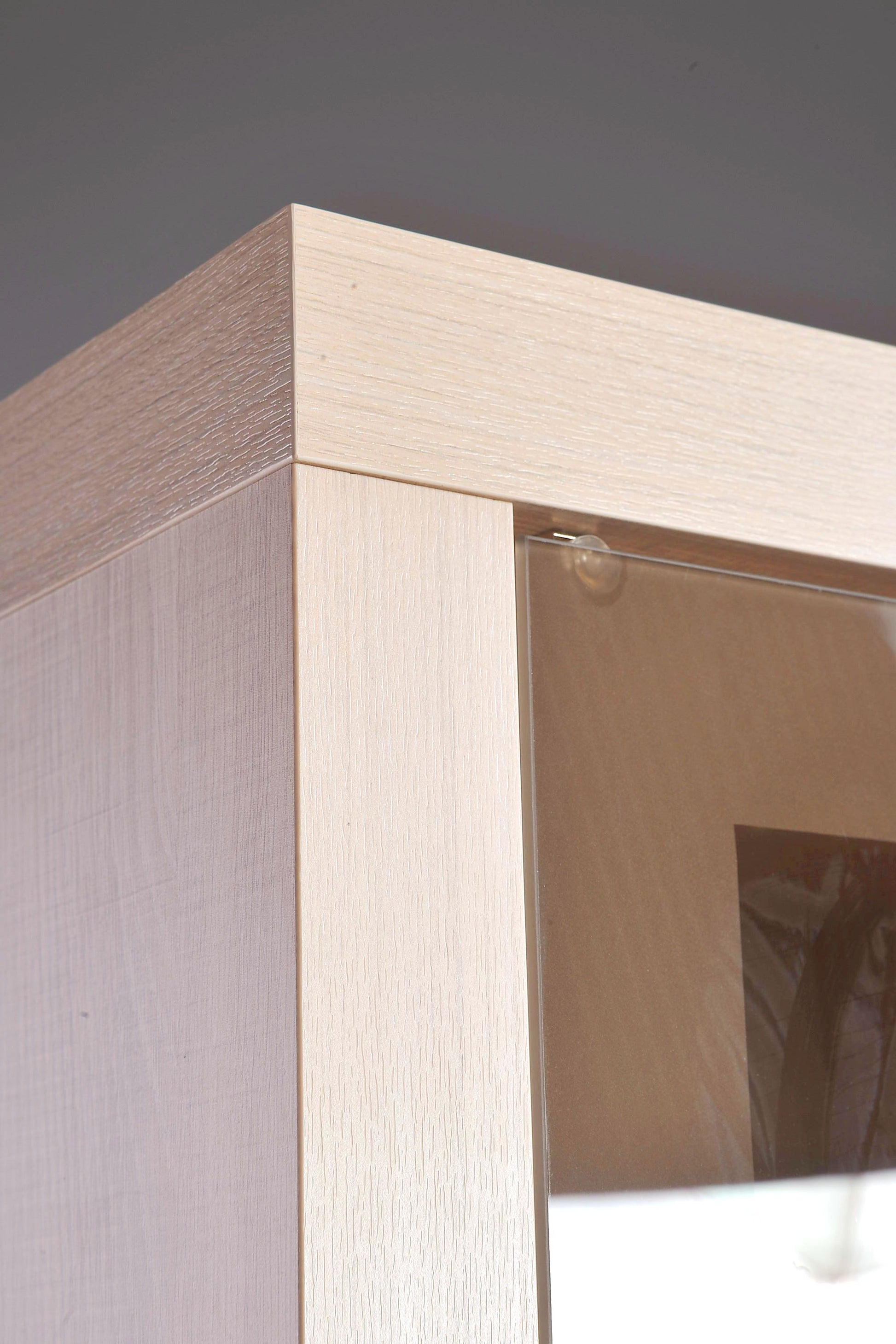 Ujęcie z boku na mebel z systemu SANTOS ukazujące estetykę wykonania, zastosowane w witrynie szkło oraz jasne wybarwienie.